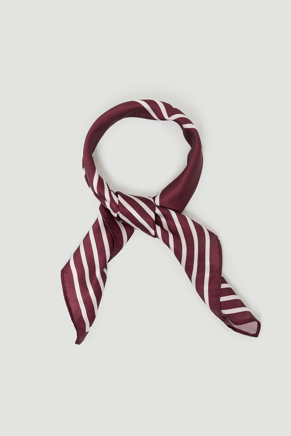 Silky plum scarf with white diagonal stripes, styled in a loose knot for a chic and versatile accessory.