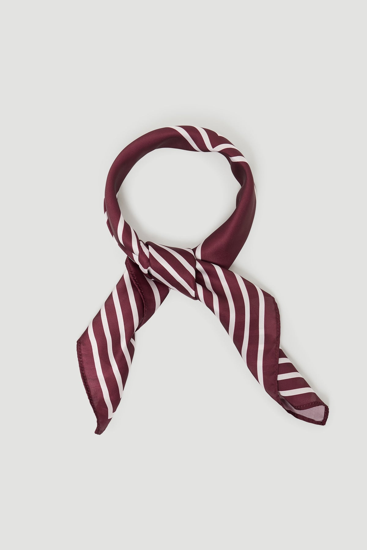 Silky plum scarf with white diagonal stripes, styled in a loose knot for a chic and versatile accessory.