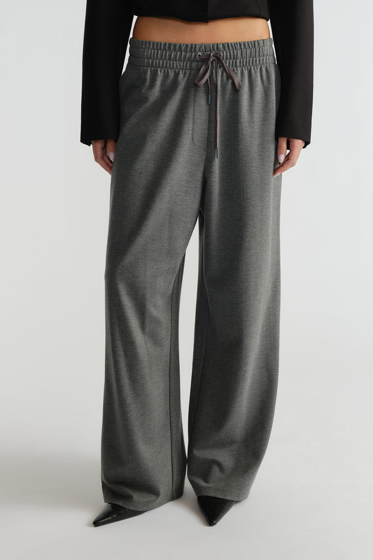 Grey wide-leg pinstripe pants with an elastic drawstring waist styled with black pointed-toe shoes and a cropped top.