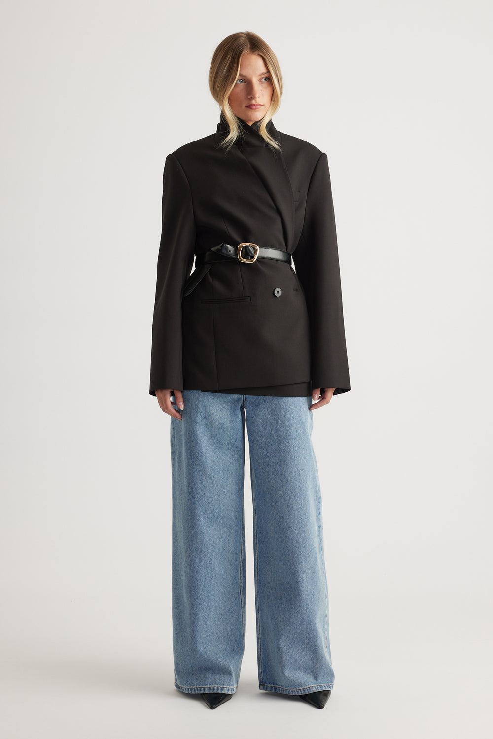 Model wearing a black belted blazer with light blue high rise wide leg jeans