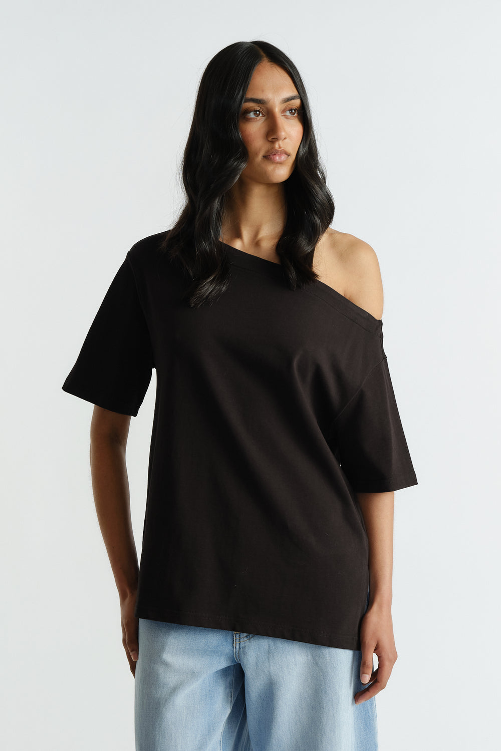 Woman wearing a black off-shoulder relaxed tee paired with light blue wide-leg denim jeans for a casual look