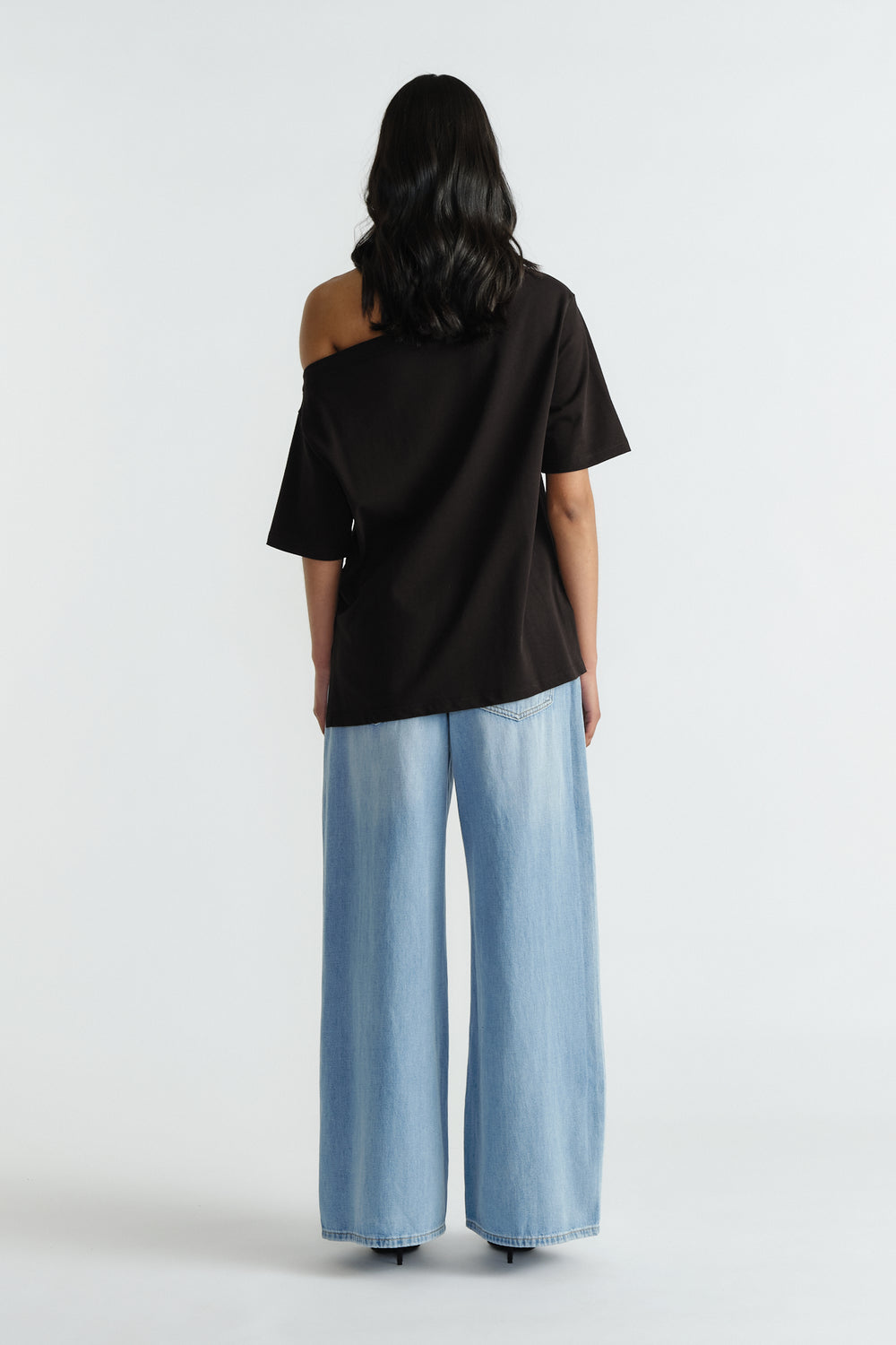 Woman wearing a relaxed black drop shoulder tee paired with wide-leg light blue denim jeans for an effortless look
