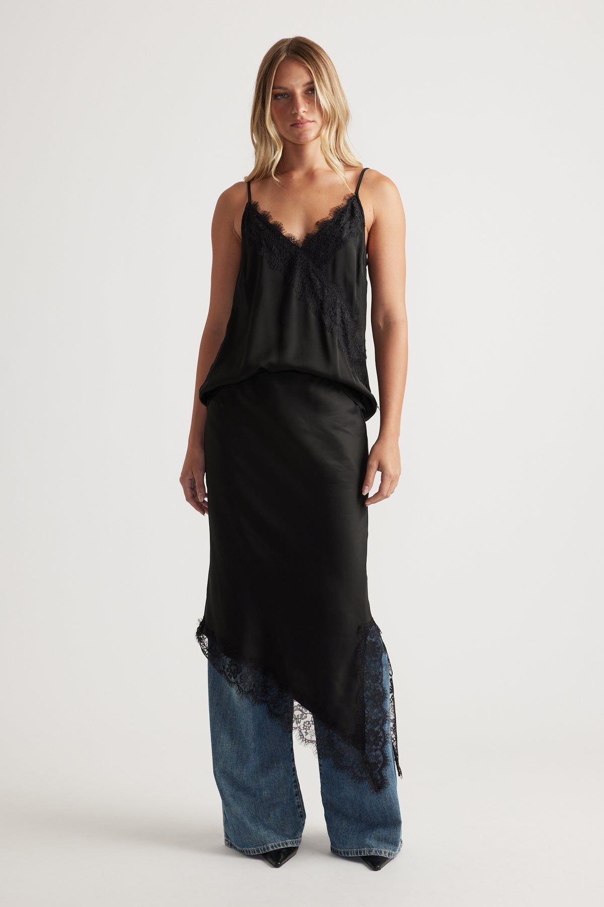 Woman wearing a black lace-trimmed cami layered over wide-leg denim jeans for an effortless, modern look.