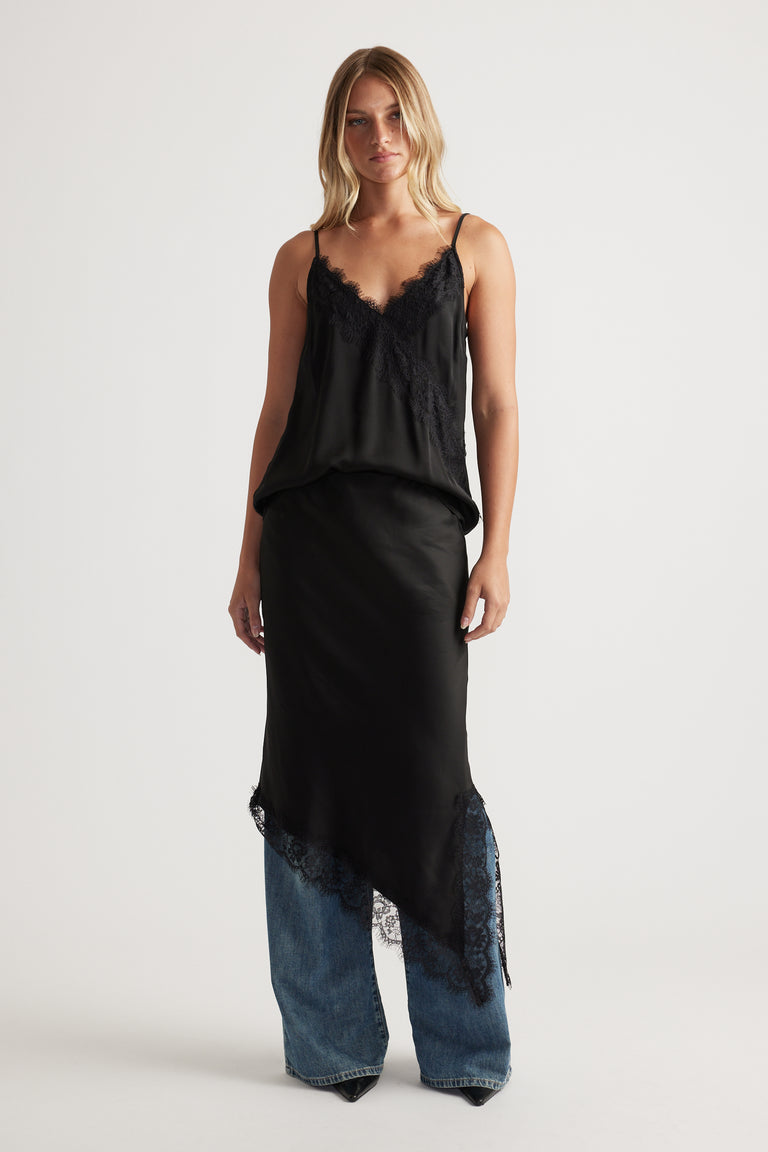 Woman wearing a black lace-trimmed cami layered over wide-leg denim jeans for an effortless, modern look.