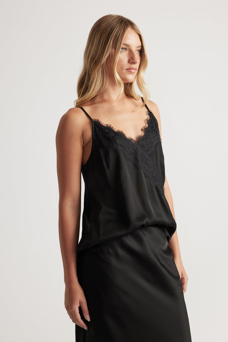 Woman wearing a sleek black cami with delicate lace trim and thin straps for an elegant, effortless look.