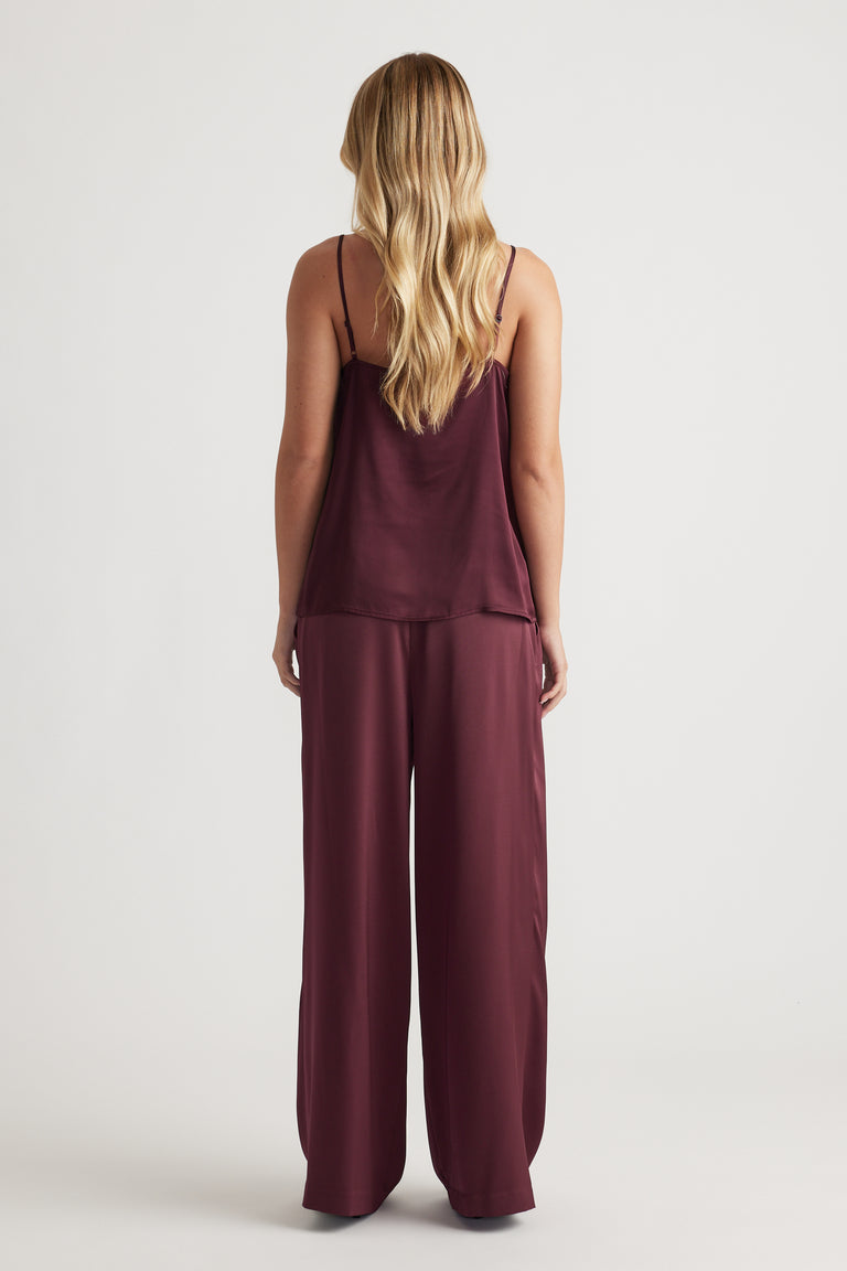 Woman wearing a plum satin camisole with thin straps paired with matching wide-leg satin pants for a sleek look