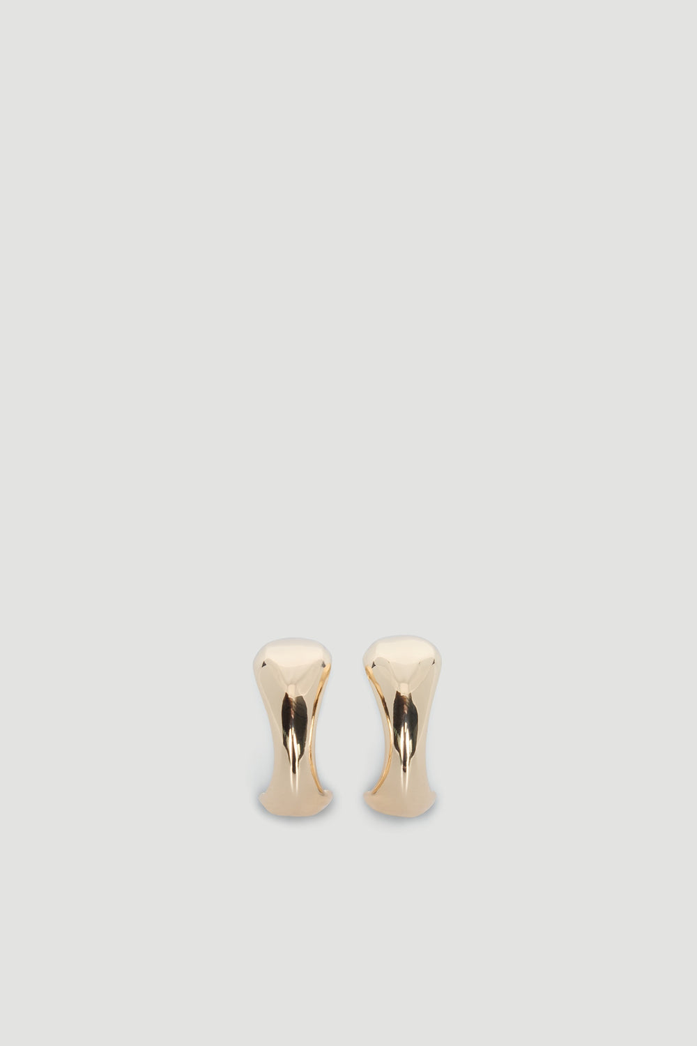 Pair of polished gold-tone abstract hoop earrings with a smooth, modern sculptural design on a neutral background.