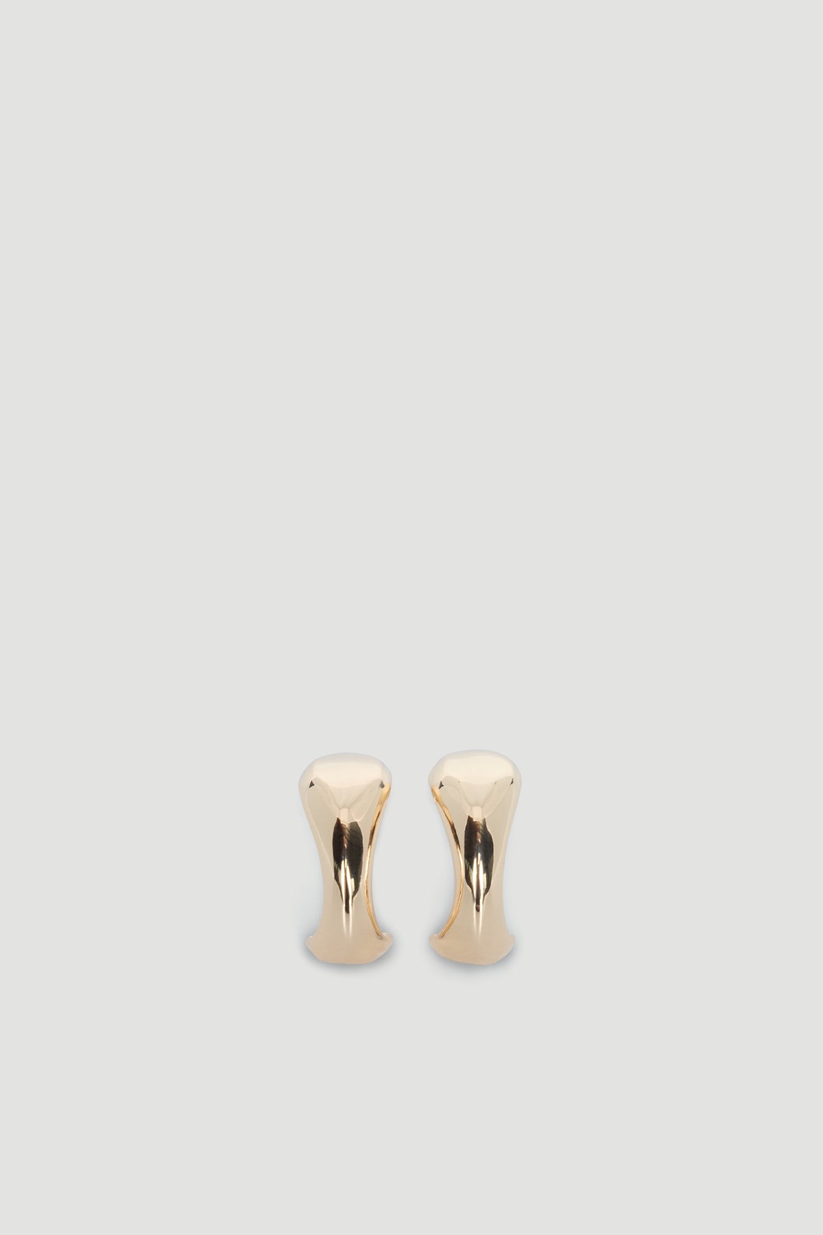 Pair of polished gold-tone abstract hoop earrings with a smooth, modern sculptural design on a neutral background.