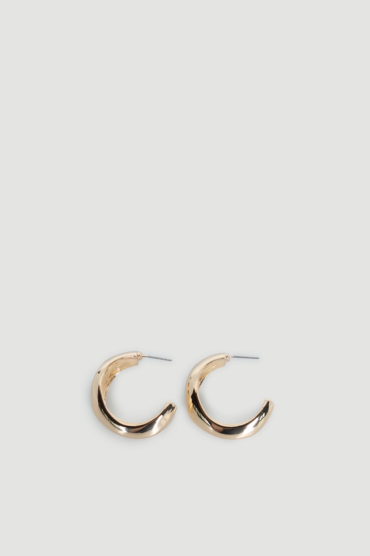 Pair of shiny gold-toned curved hoop earrings with a smooth, abstract design on a light background