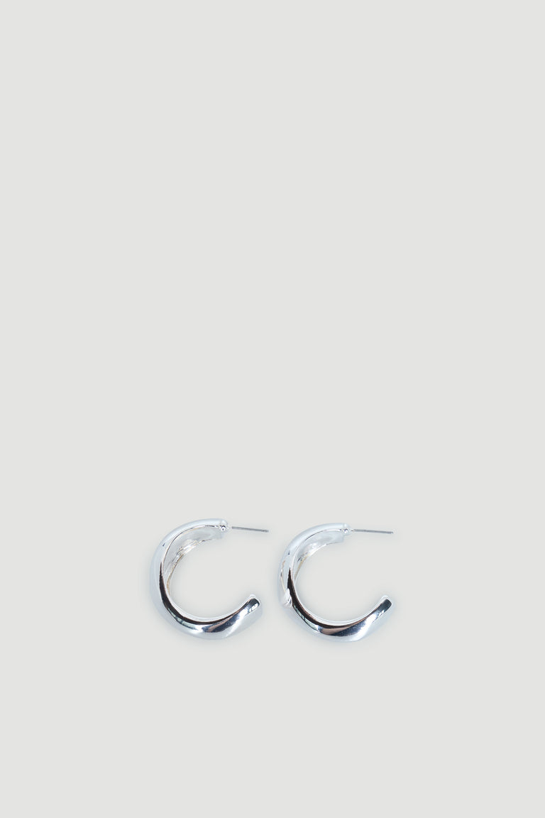 Pair of polished silver hoop earrings with an abstract, slightly chunky curved design on a light background.