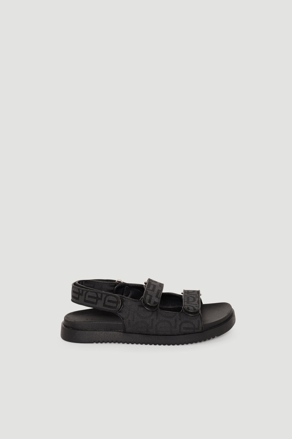 Black adjustable sandals featuring monogram straps and a cushioned sole for stylish everyday comfort.