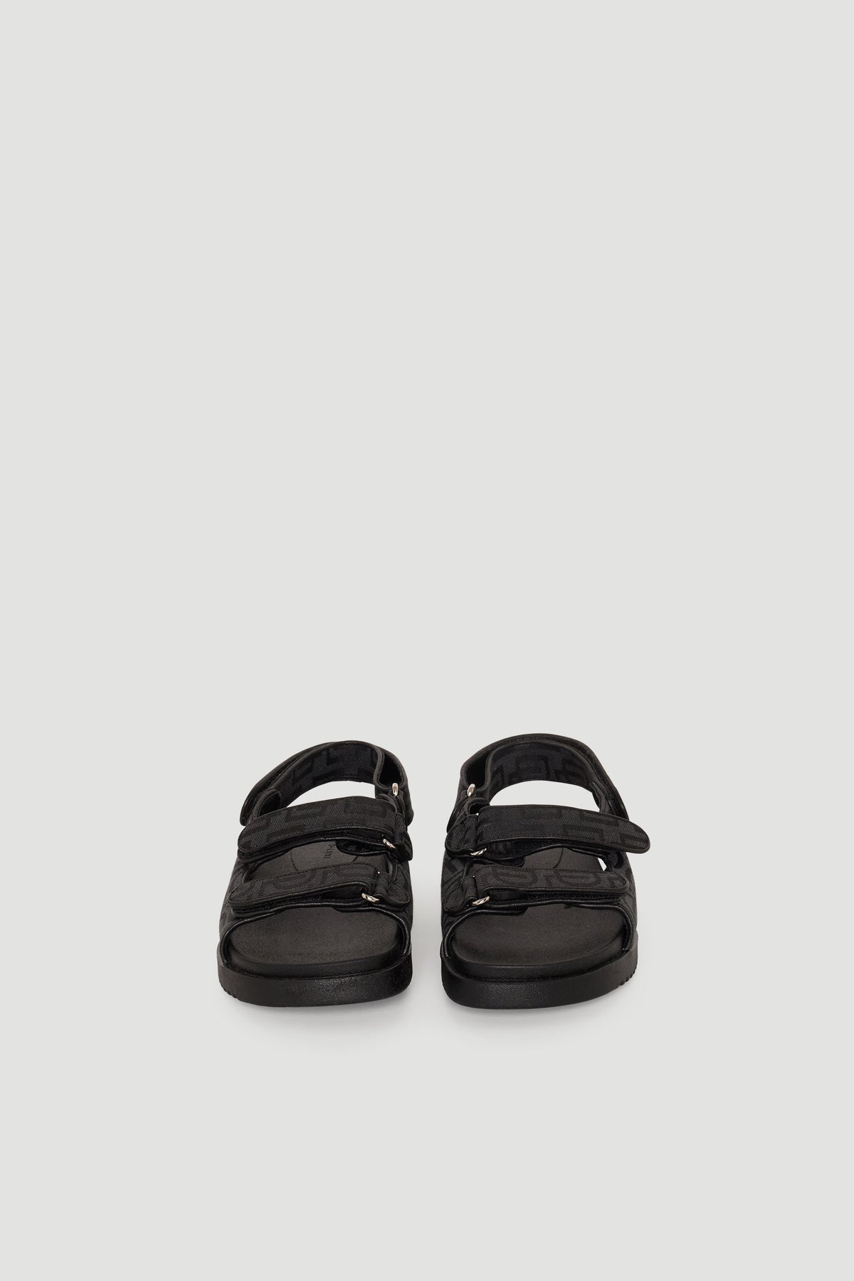 Pair of black sandals featuring adjustable straps and chunky soles with subtle monogram detailing for everyday wear.