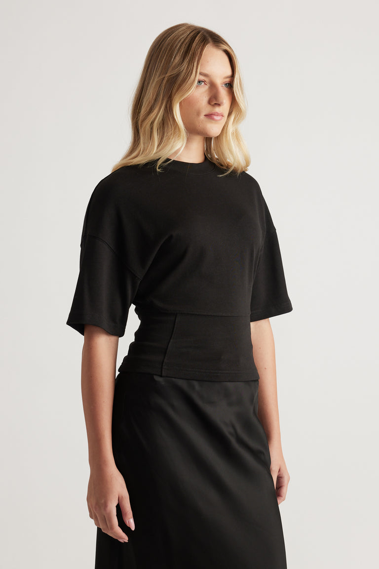 Woman in a black fitted waist tee with short sleeves paired with a sleek black skirt for a polished look