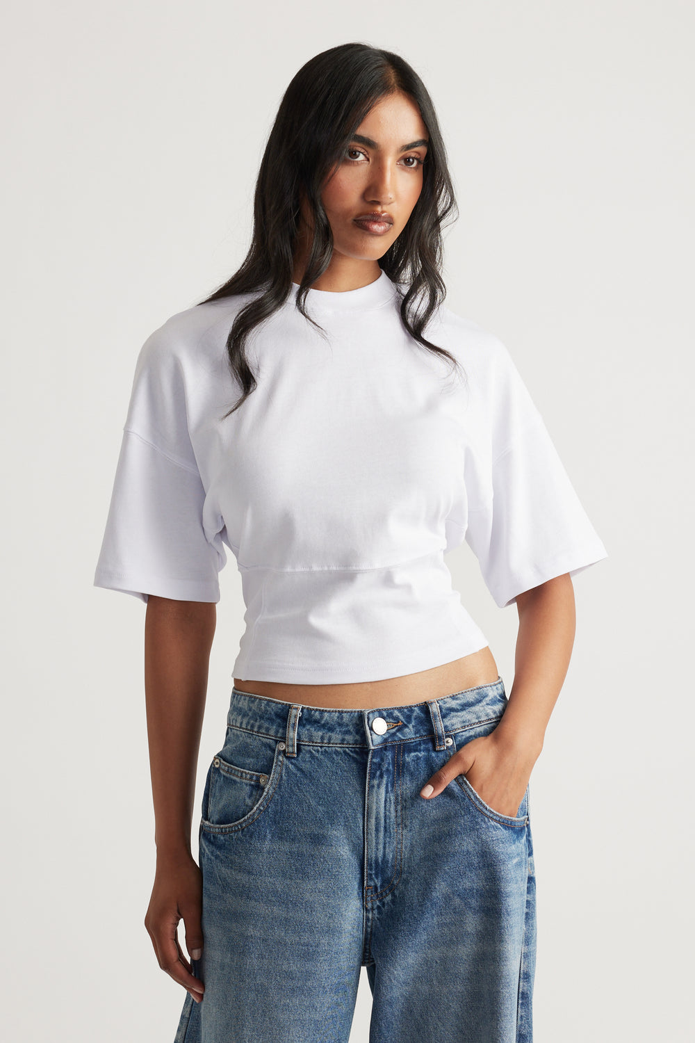 Woman wearing a fitted white tee with a high neckline paired with relaxed medium-wash denim jeans for a modern casual look