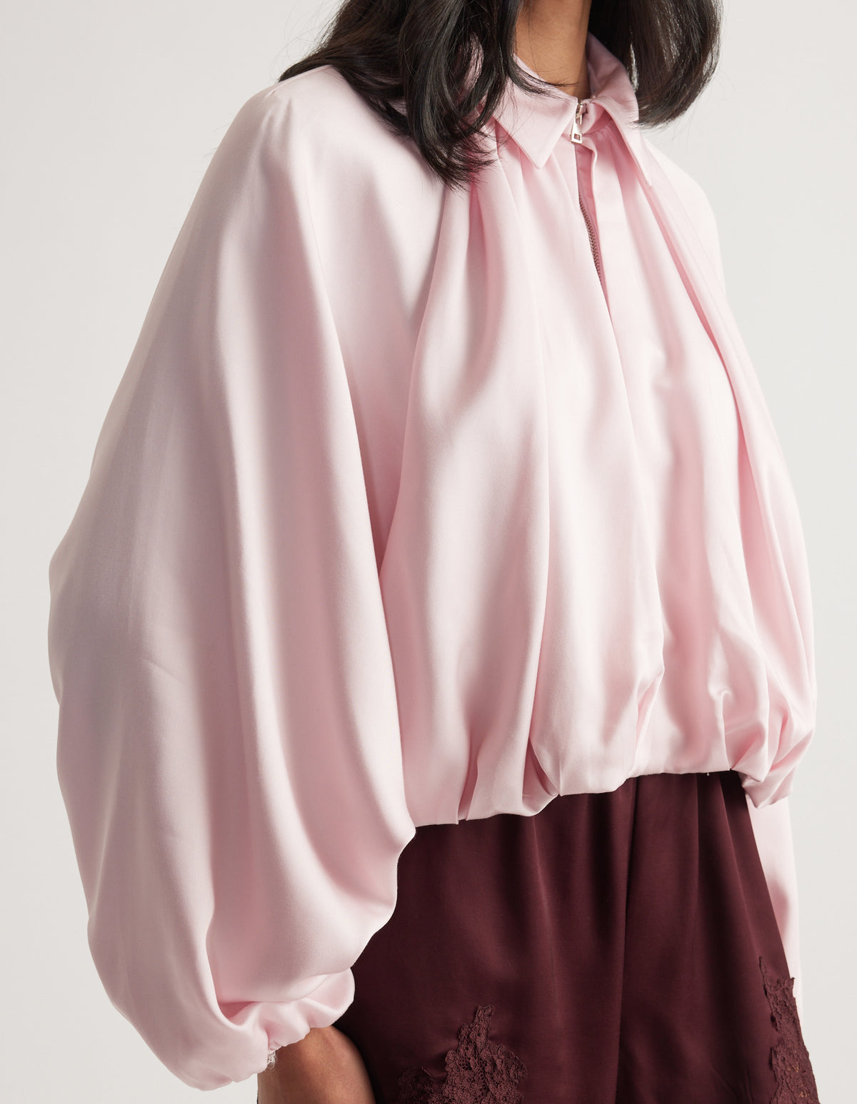 Light pink relaxed zip-front jacket with voluminous sleeves styled with burgundy pants