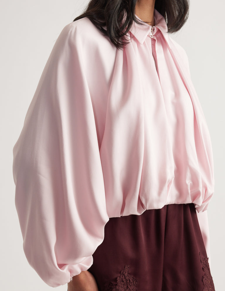 Light pink relaxed zip-front jacket with voluminous sleeves styled with burgundy pants