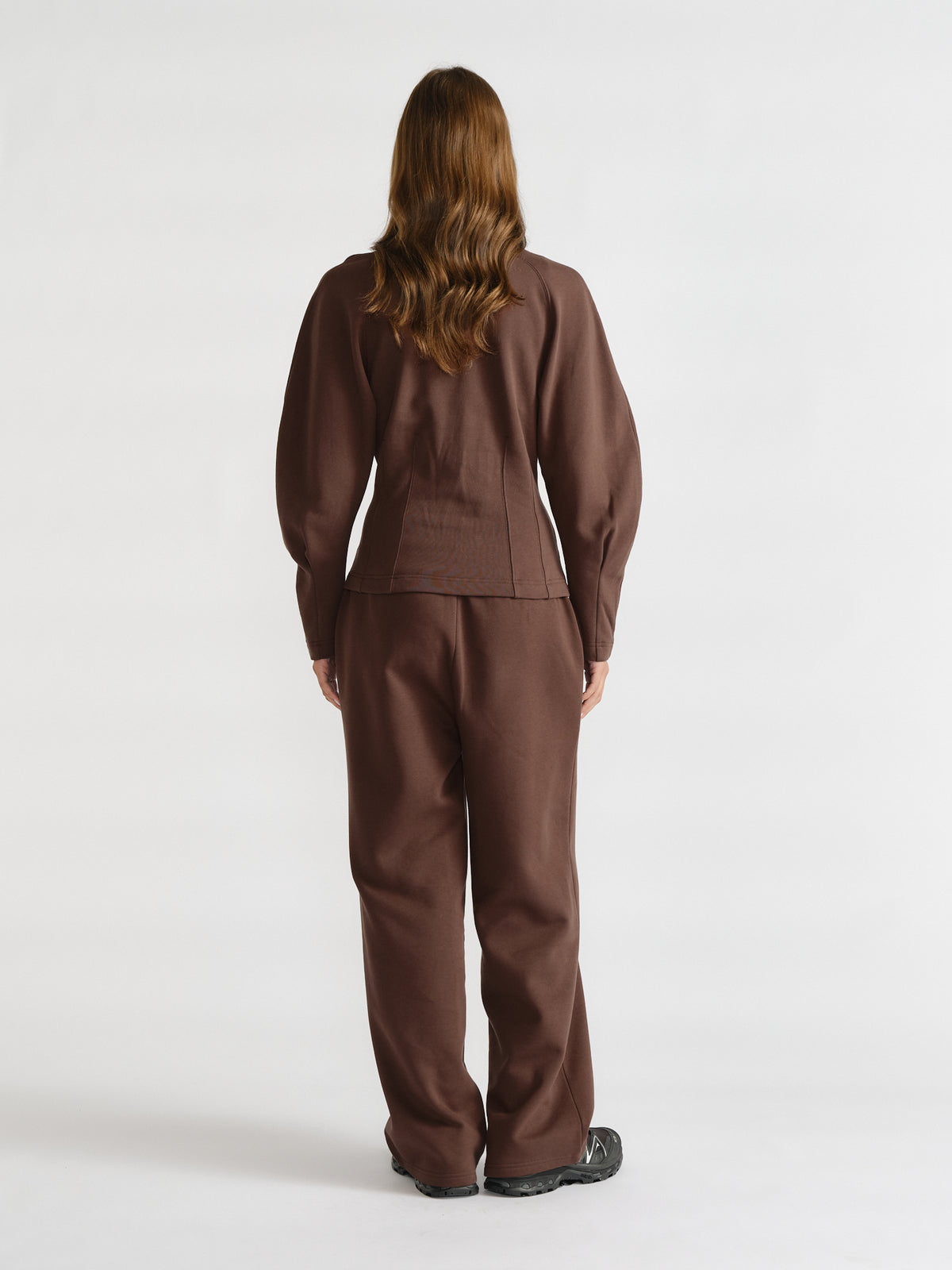 Woman wearing a walnut brown cinched waist sweatshirt and matching relaxed pants, styled for a cozy casual look