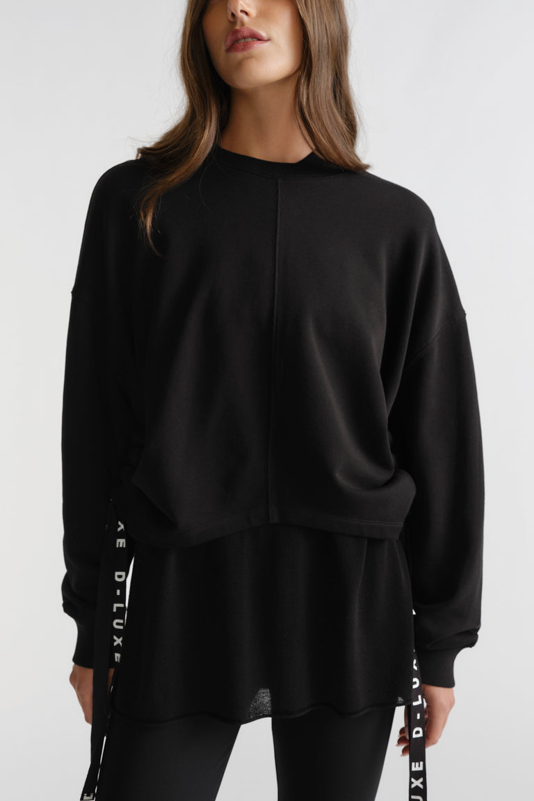 Woman wearing black D-Luxe Ruched Terry Sweat with relaxed fit, ruched sides, and subtle logo straps for casual style.