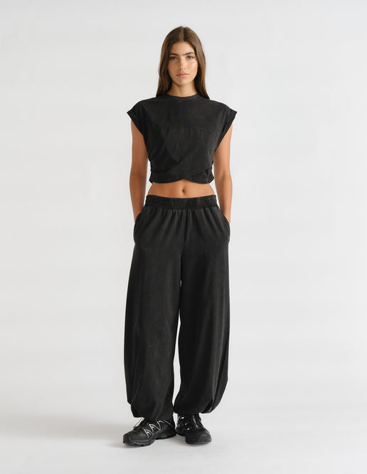 Woman wearing black balloon joggers with an elastic waist and cropped sleeveless top