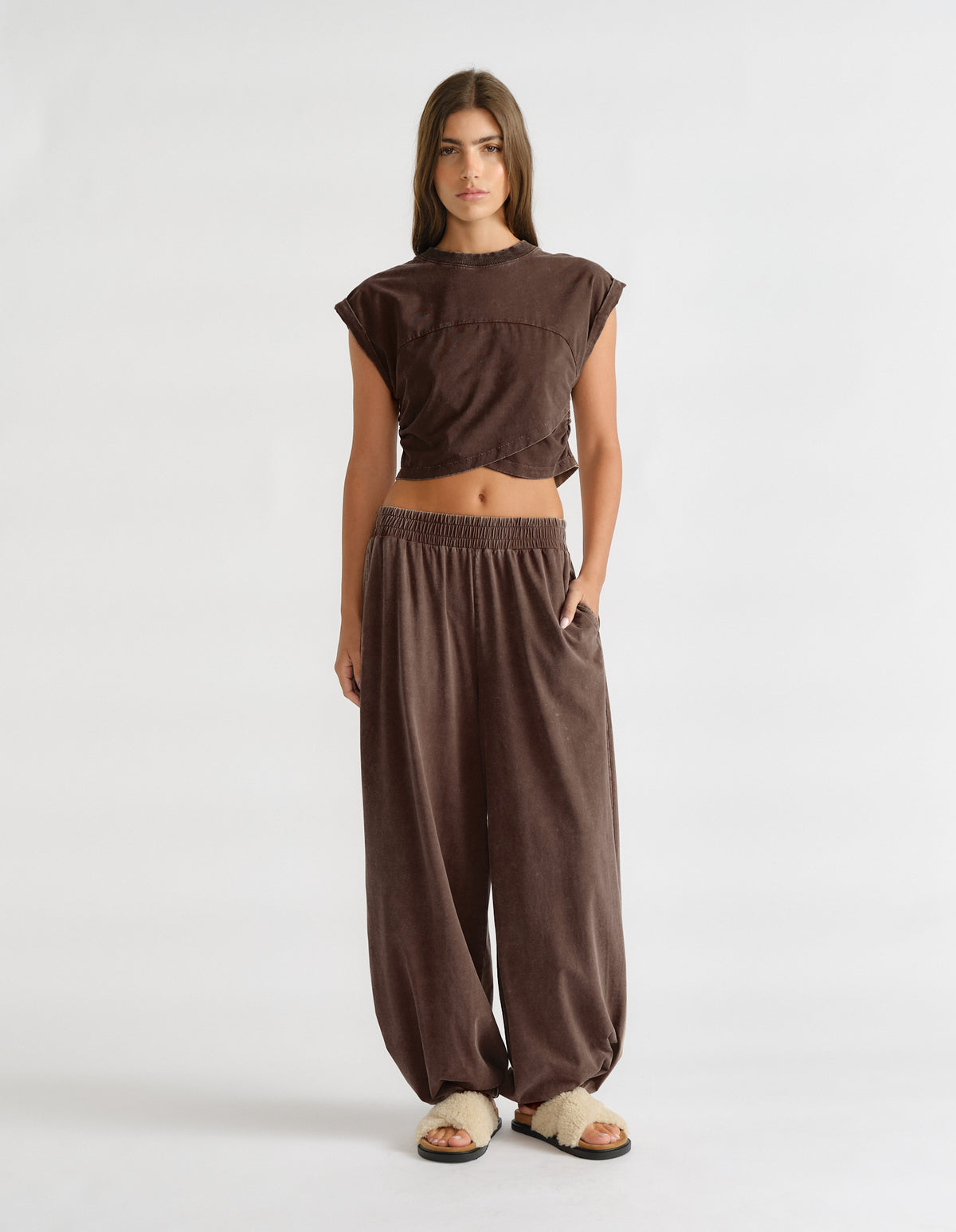 Woman wearing brown balloon joggers with an elastic waistband, side pockets and gathered hems