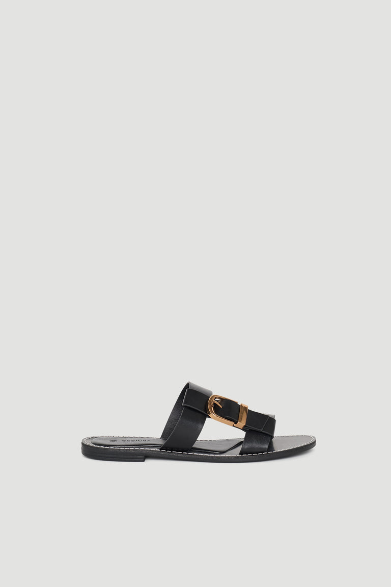 Black leather slide sandal featuring a wide strap with a gold buckle for a chic, minimalist look.