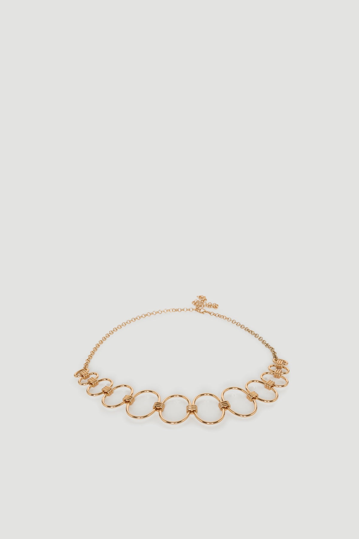 Gold-tone chain belt featuring interconnected circular links with adjustable clasp closure for a polished finish