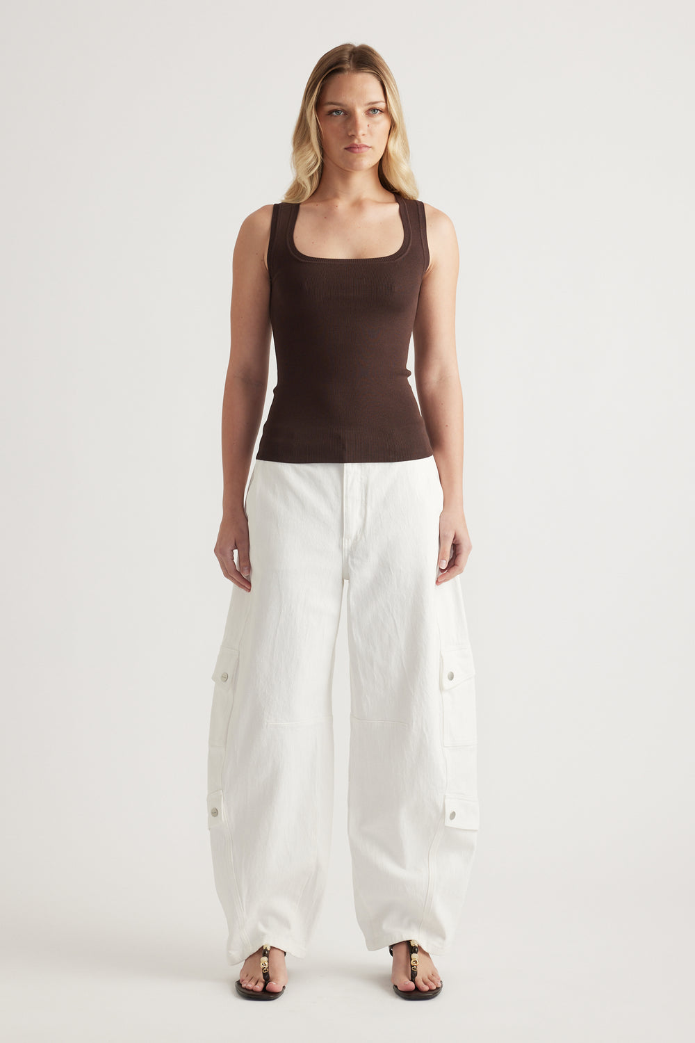 Woman wearing a brown square neck knit tank with white wide leg cargo pants and sandals