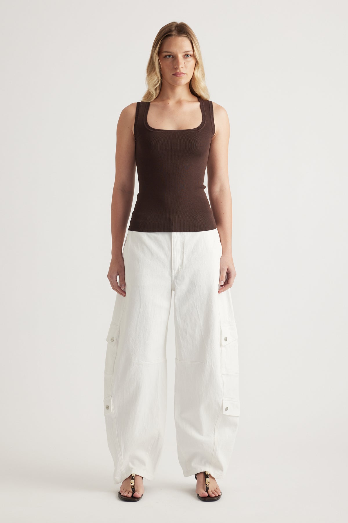 Woman wearing a brown square neck knit tank with white wide leg cargo pants and sandals