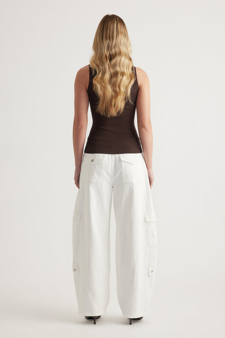 Woman wearing a fitted brown sleeveless tank with white cargo pants, viewed from behind