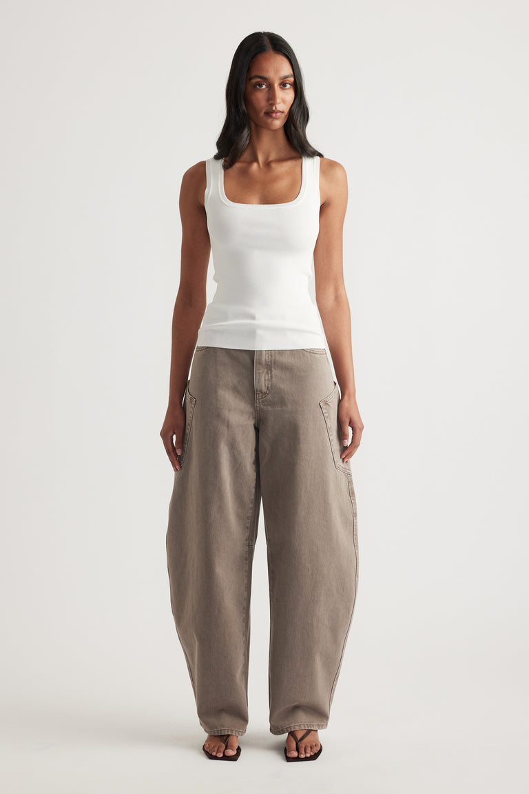 Woman wearing a white fitted square-neck tank top with taupe balloon-leg pants and sandals
