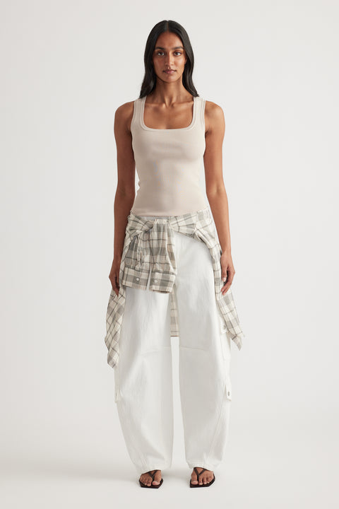 Woman wearing a beige square neck knit tank with white cargo pants and plaid shirt tied at the waist