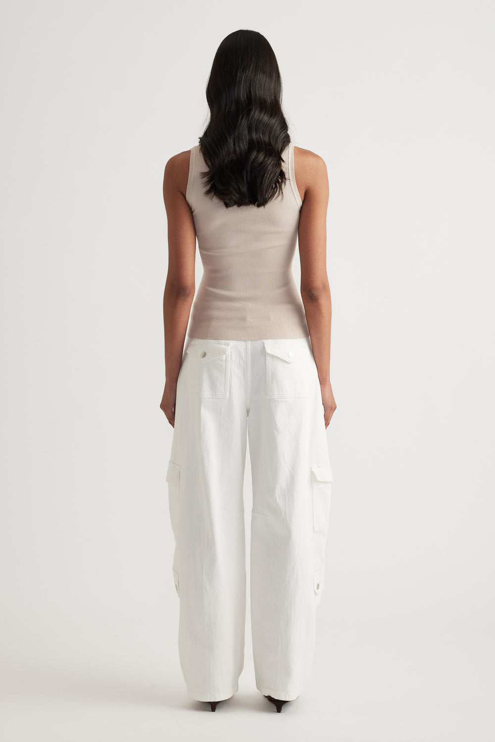 Woman viewed from behind wearing a beige fitted knit tank and white wide-leg cargo pants