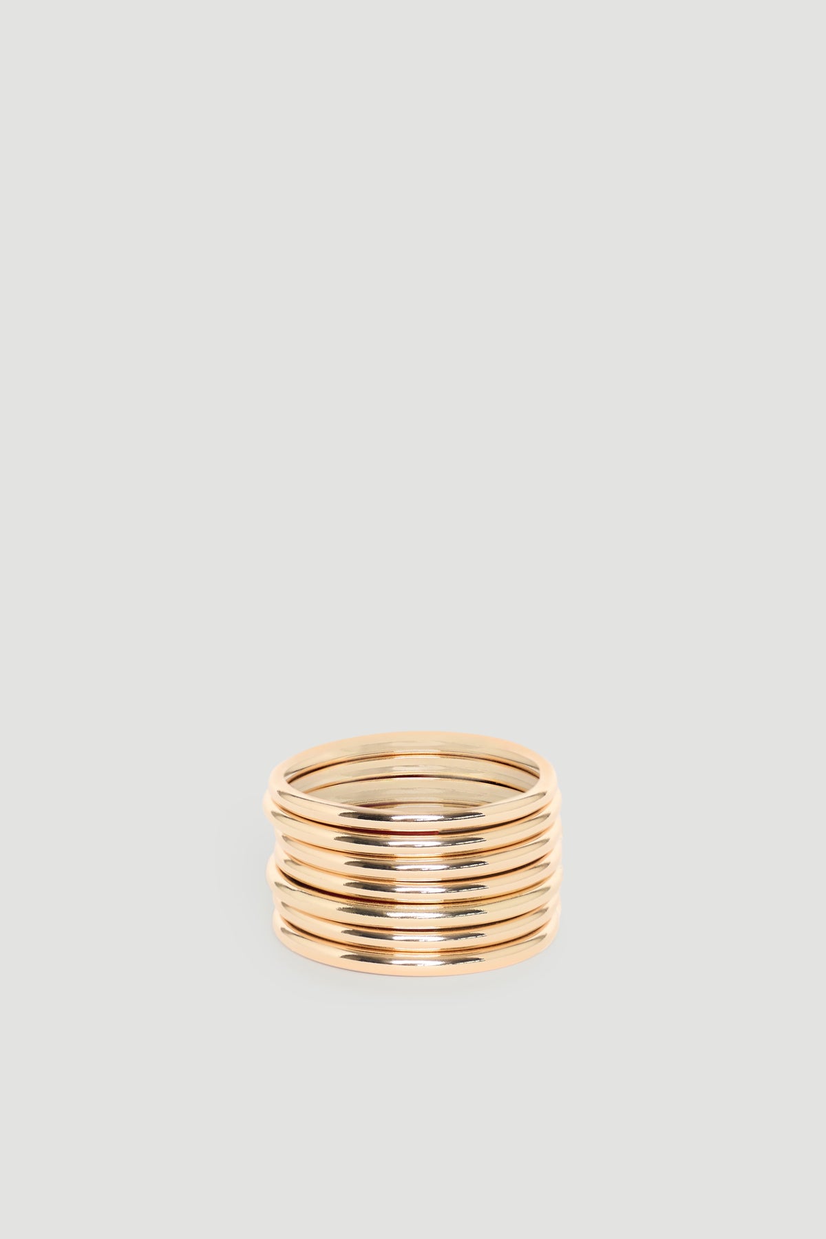 Stack of polished gold-tone bangles with smooth, rounded edges for a timeless and versatile accessory look