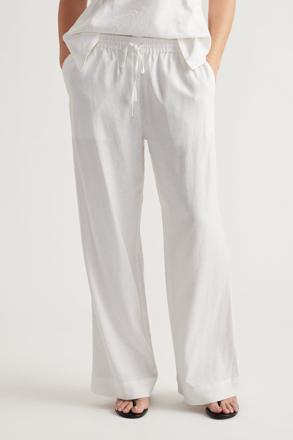 Relaxed white linen blend pants with elastic waistband and drawstring, styled for effortless everyday comfort.