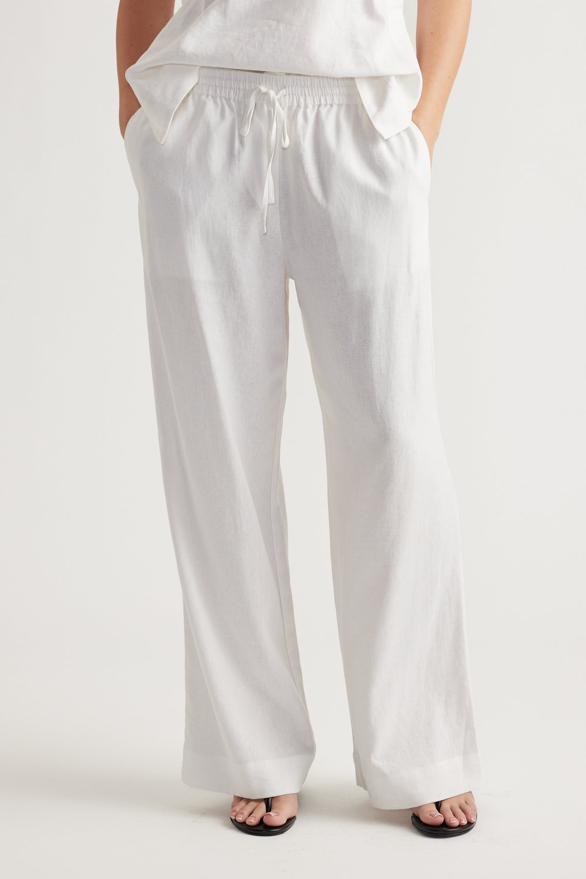 Relaxed white linen blend pants with elastic waistband and drawstring, styled for effortless everyday comfort.