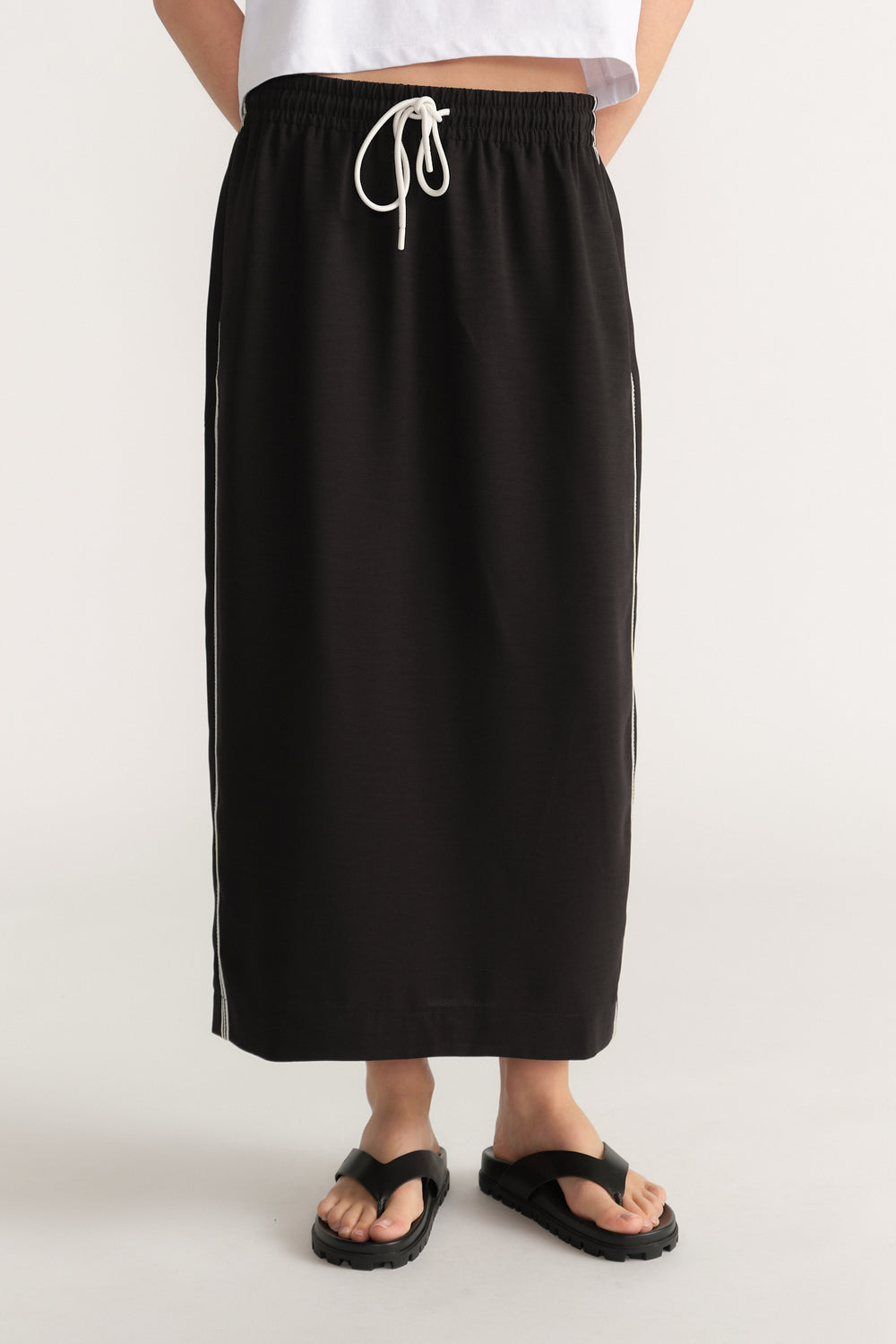 Woman wearing a black midi pencil skirt with an elastic drawcord waist and side stripe