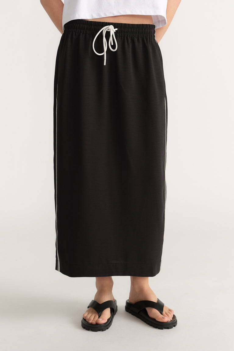Woman wearing a black midi pencil skirt with an elastic drawcord waist and side stripe