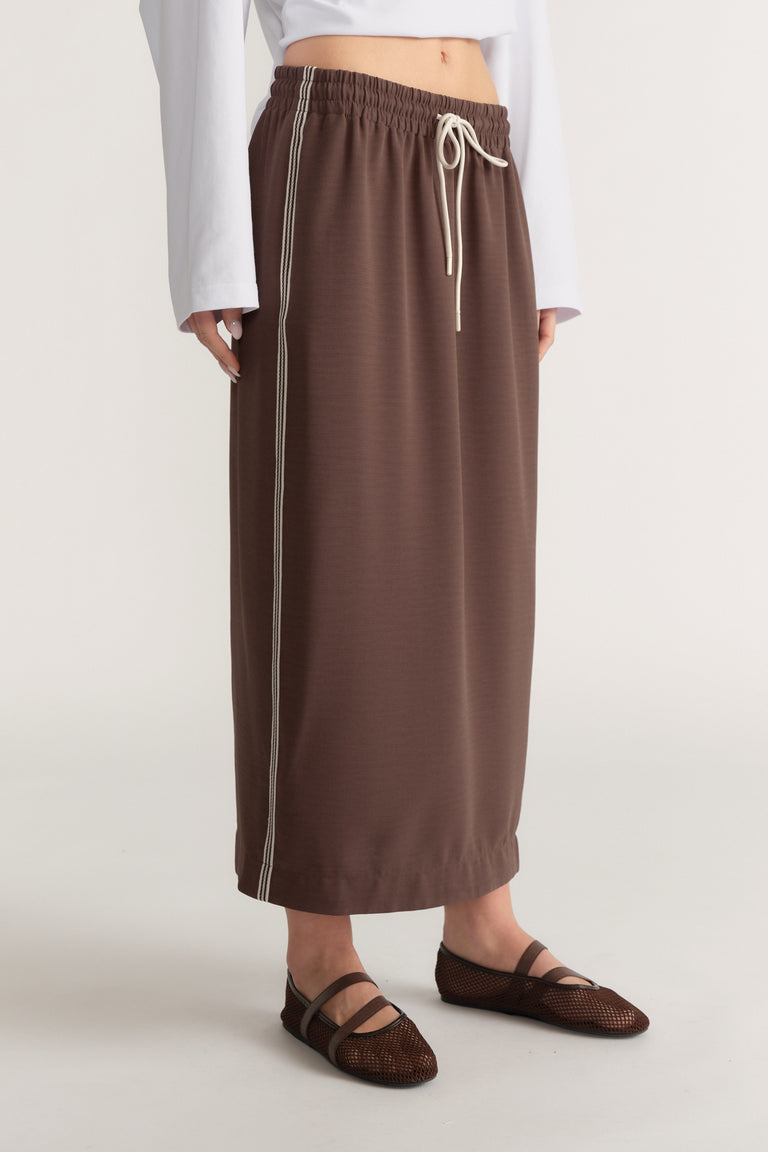 Brown drawcord midi skirt with side racer stripes, styled with a white cropped top and woven flats