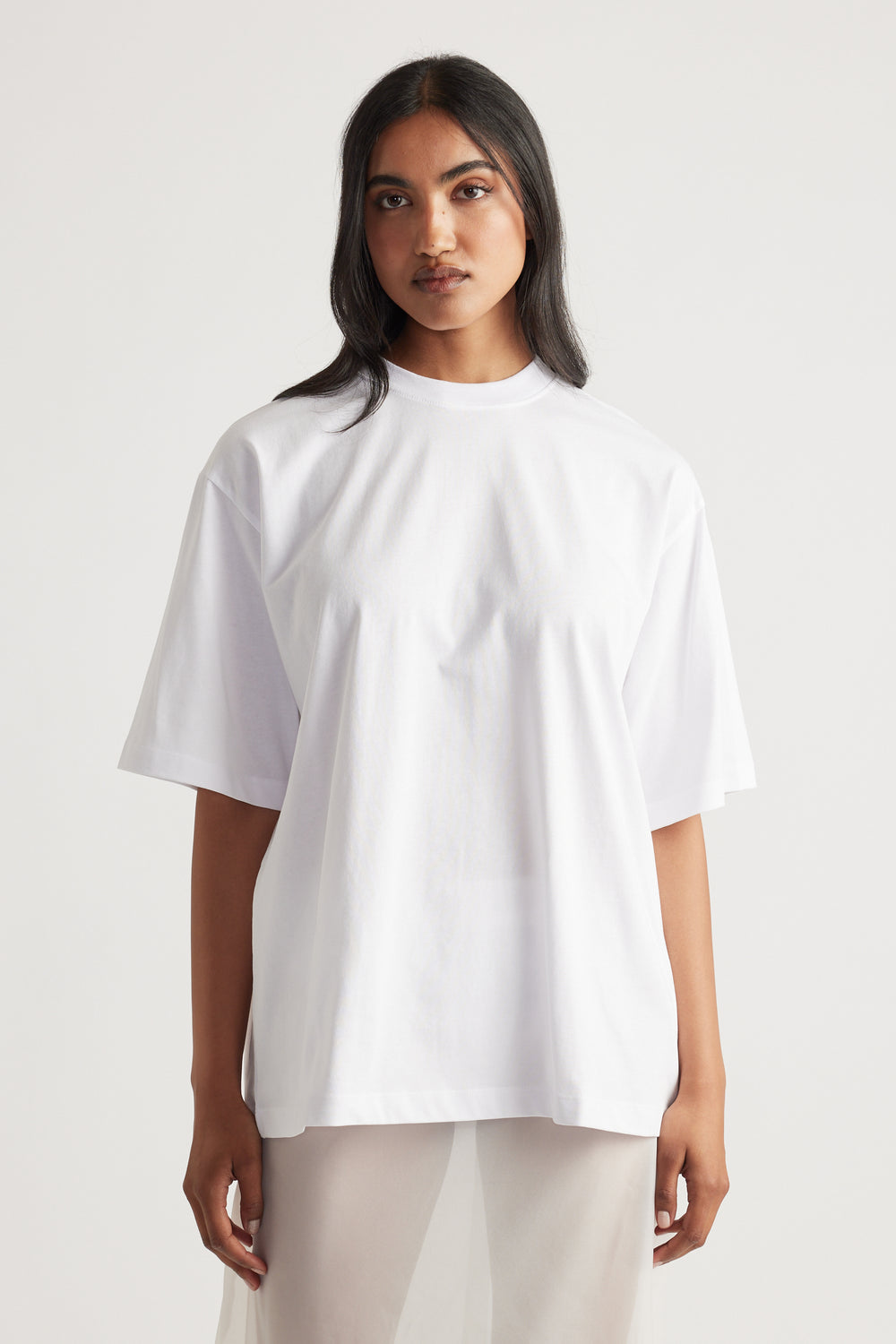 Front view of woman wearing a bright white oversized tee with relaxed short sleeves and a crew neckline