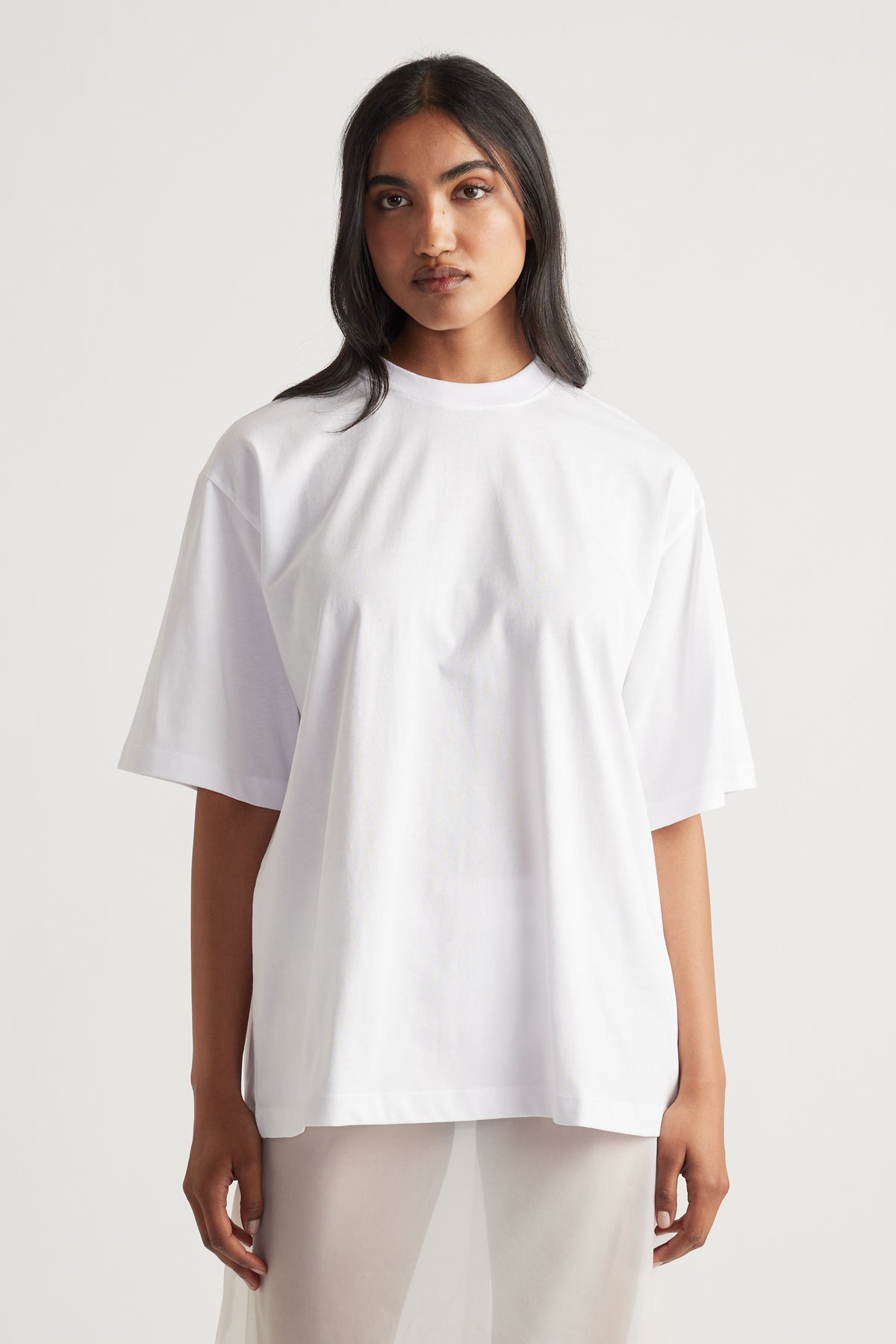 Front view of woman wearing a bright white oversized tee with relaxed short sleeves and a crew neckline