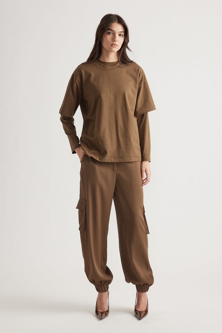 Woman wearing relaxed fit brown cargo pants with cuffed ankles paired with a layered oversized brown tee and pointed heels