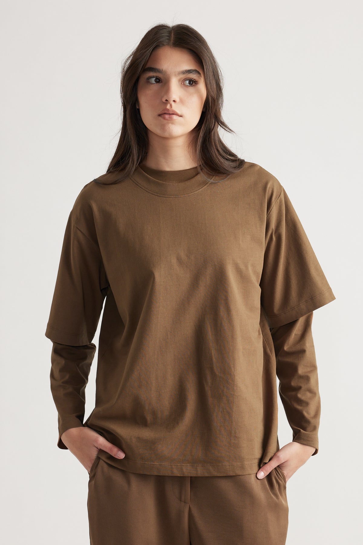 Woman wearing a relaxed-fit brown oversized tee styled over a matching long-sleeve top and pants for an effortless look