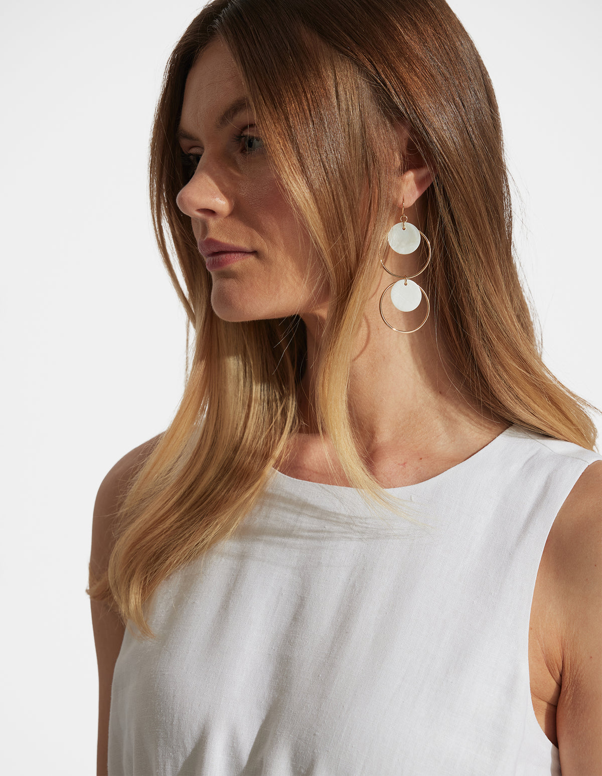 Tina Circle Earrings featuring delicate gold hoops and mother-of-pearl discs, styled with a white sleeveless top by DECJUBA Australian brand