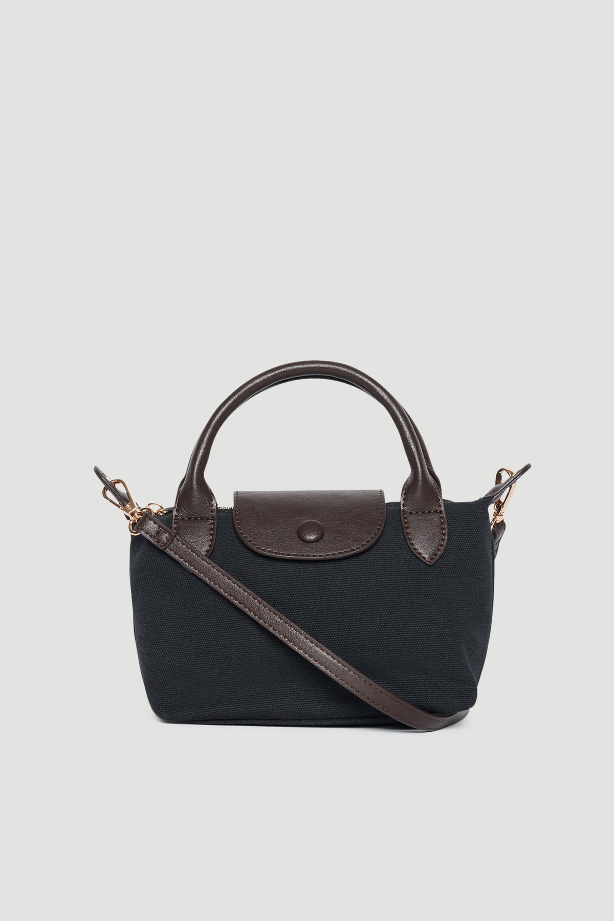 Black mini top handle bag with brown trim, double handles, flap closure and detachable crossbody strap