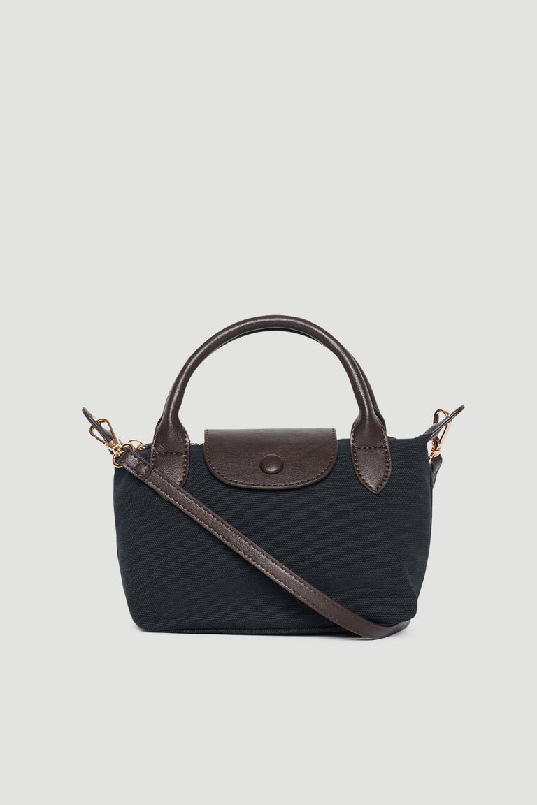 Black mini top handle bag with brown trim, double handles, flap closure and detachable crossbody strap