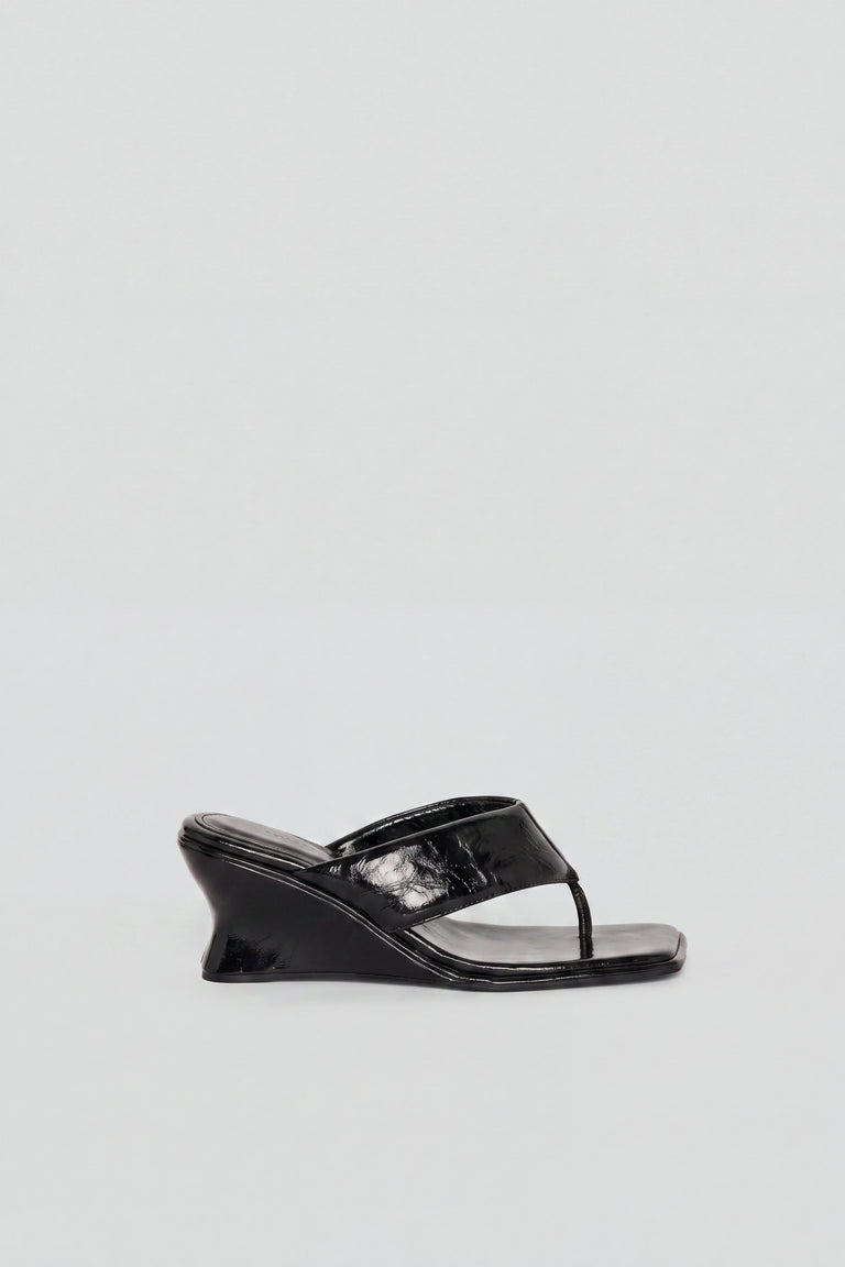 Side view of black glossy wedged thong heel sandal with sculptural heel and toe post detail