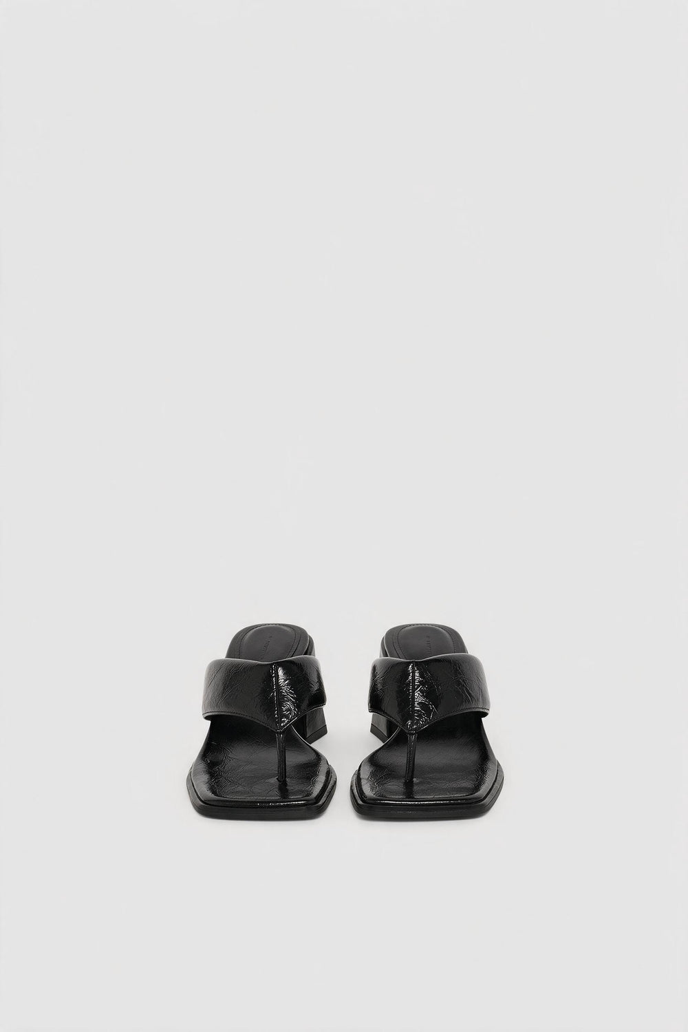 Pair of black sculptural wedge thong sandals with square toe and wide strap upper viewed from front