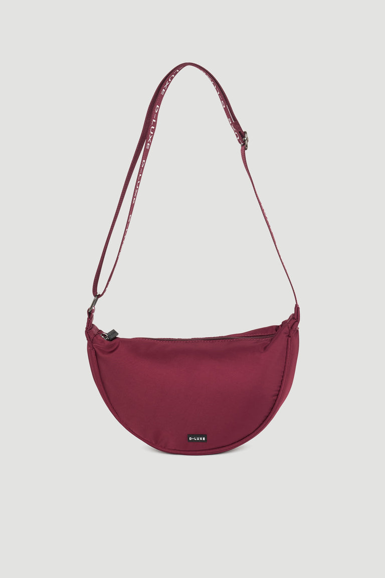Plum half moon crossbody bag with adjustable branded strap and subtle logo detail on front panel