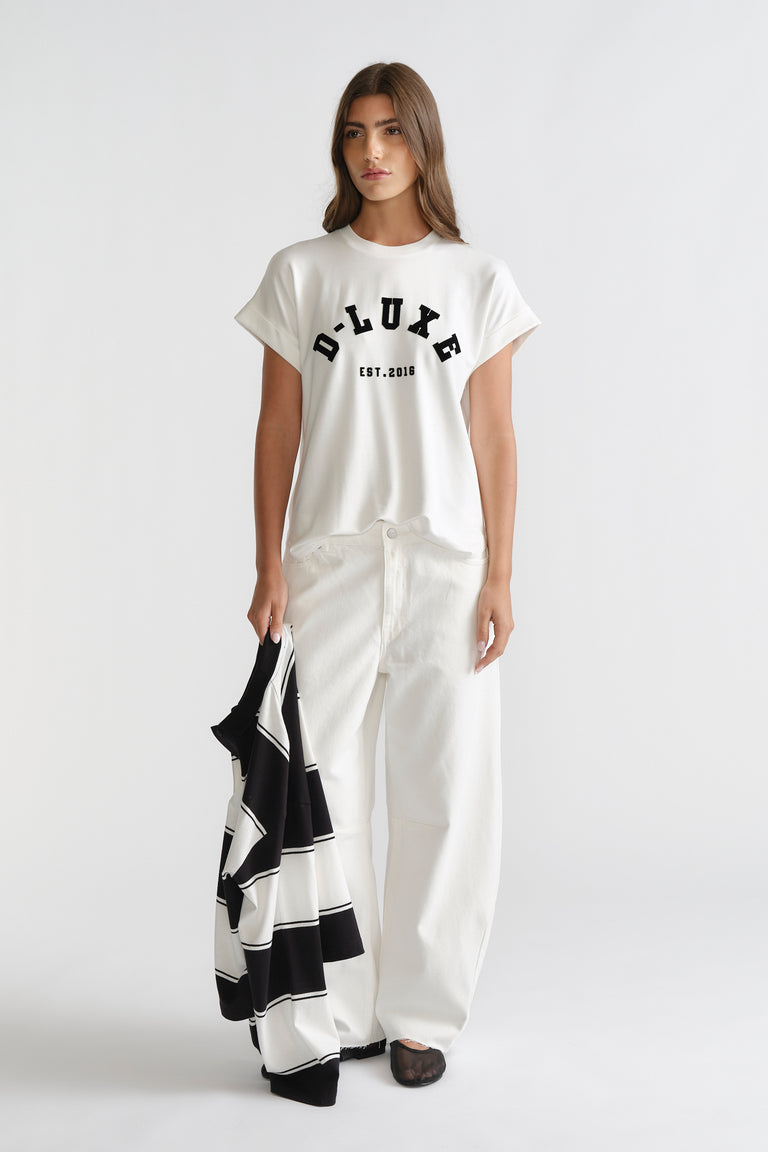 D-Luxe Half Moon Tee in white with bold black lettering, styled with relaxed white wide-leg denim by DECJUBA Australian brand.