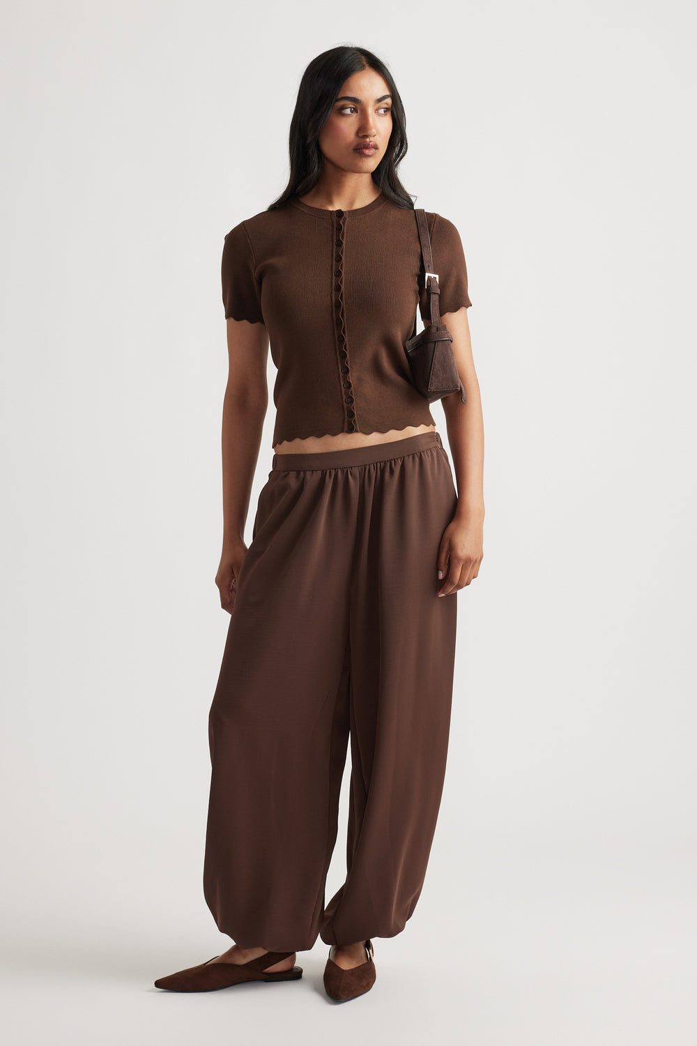 Woman wearing Maya Scallop Trim Button Top in warm coffee brown with delicate scalloped edges, styled with matching relaxed pants by DECJUBA